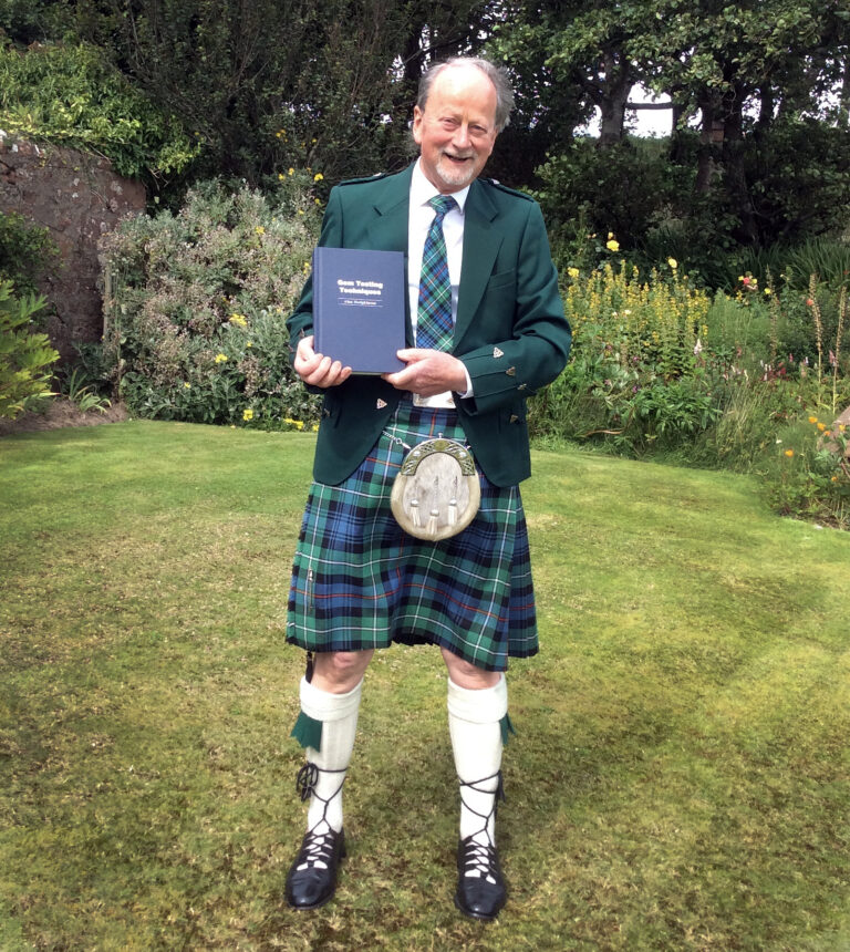 Scottish gemologist Alan Hodgkinson holding his Gem Testing Techniques book.